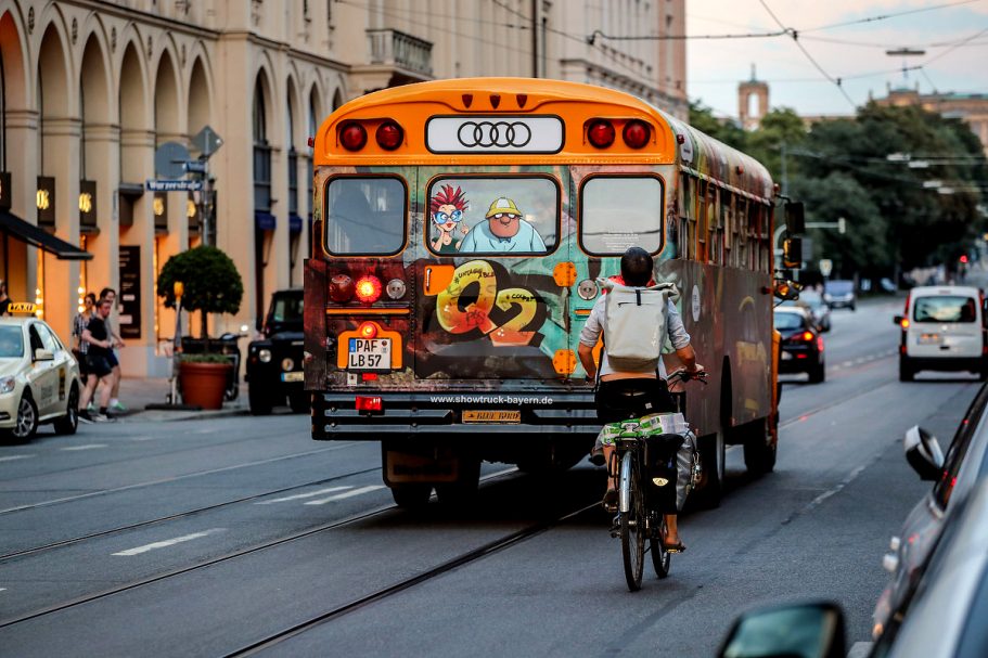 Farbige, bemalte Schulbus mit Graffiti fährt auf der Straße, Fahrradfahrer passiert.