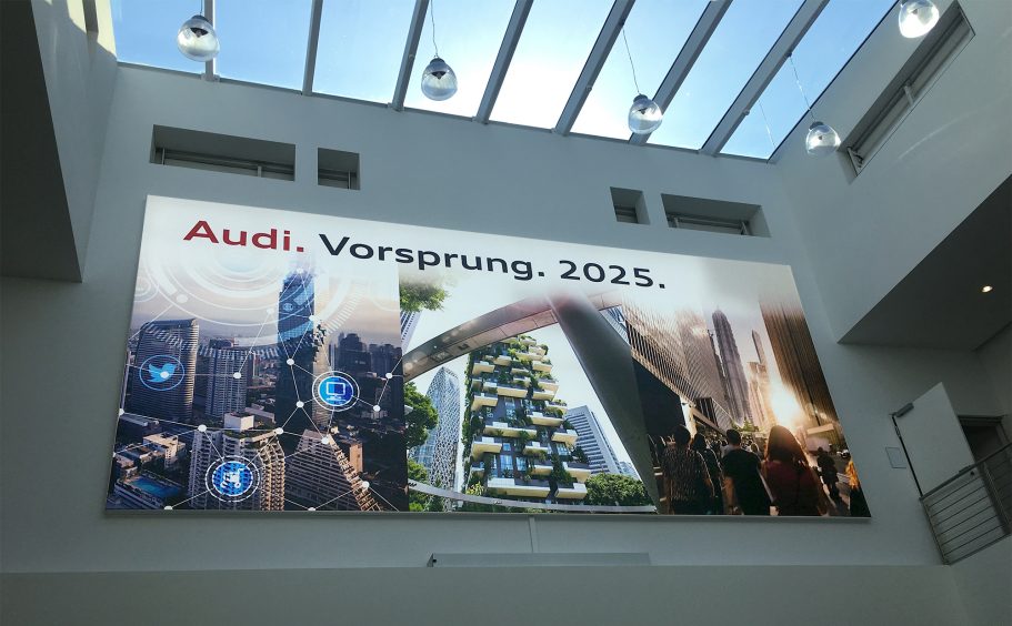 Großes Banner mit dem Text "Audi, Vorsprung, 2015" und modernen Stadtansichten.