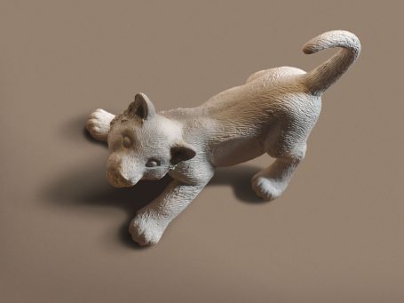 Hellbraune Hundeskulptur, die auf dem Boden sitzt und den Betrachter ansieht.