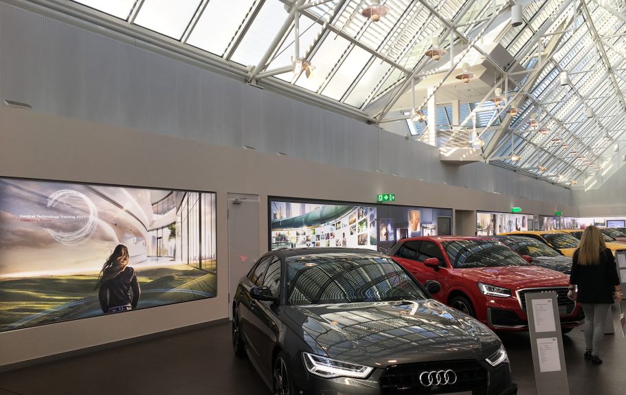 Moderne Autos in einer hellen Ausstellungsfläche mit Kunstwerken im Hintergrund.