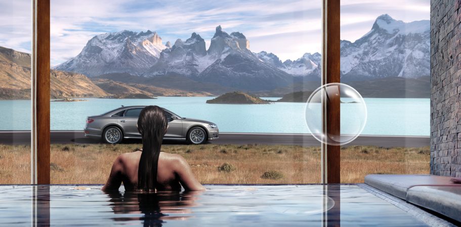 Person im Whirlpool blickt auf Berge und See, während ein Auto in der Nähe steht.